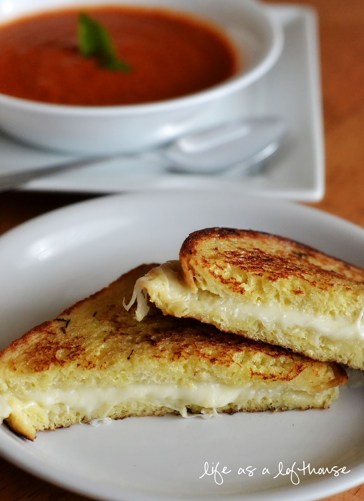 Grilled Mozzarella Cheese Sandwiches on a dish with Tomato Basil Soup in the background