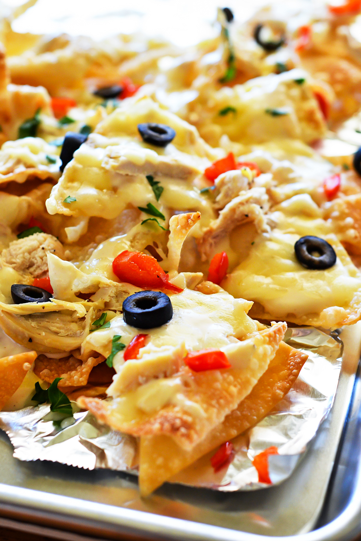 These Italian nachos are made with crispy wontons, grilled chicken, bell peppers, and olives smothered in&nbsp;Alfredo sauce and cheese. Life-in-the-Lofthouse.com