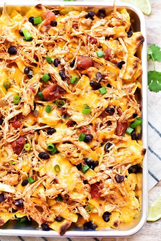 Sheet Pan Chicken Nachos are a must-make for game day or any party! Seasoned shredded chicken, black beans, cheese and more all loaded on top of tortilla chips!