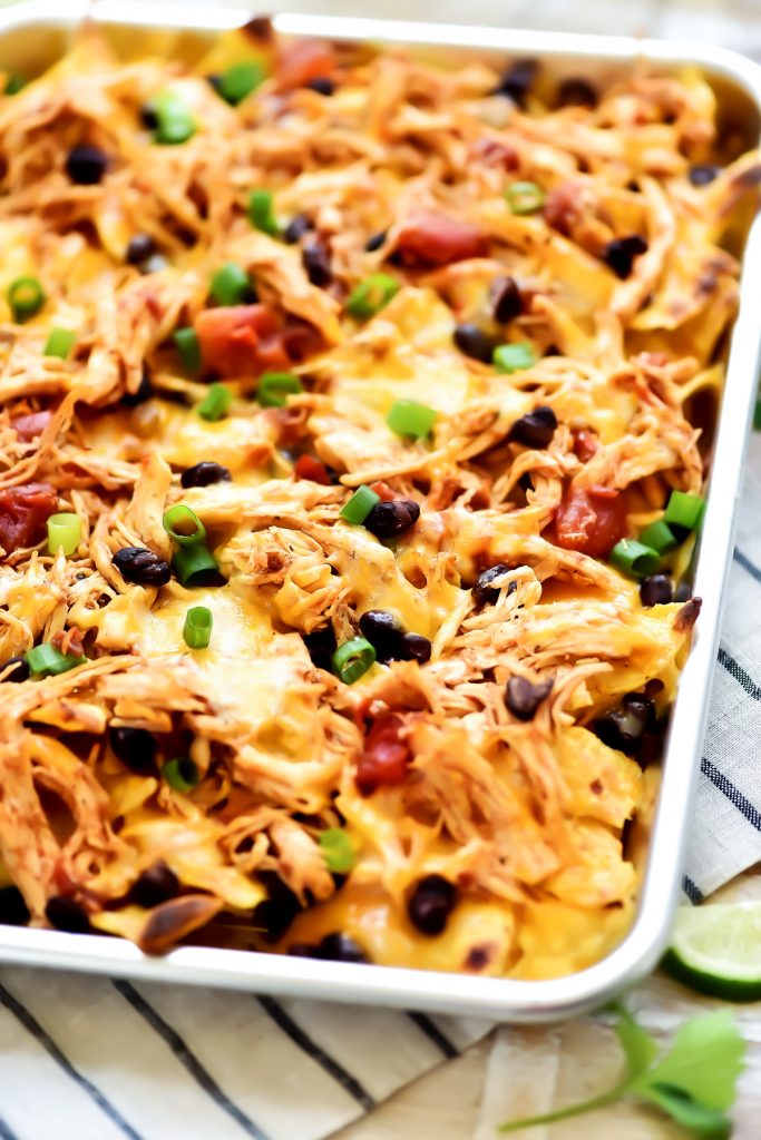 Sheet Pan Chicken Nachos are a must-make for game day or any party! Seasoned shredded chicken, black beans, cheese and more all loaded on top of tortilla chips!