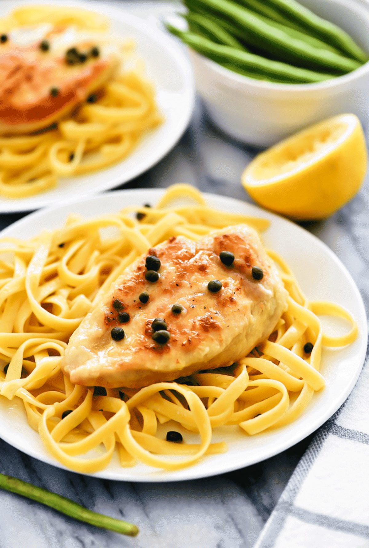 Easy Chicken Piccata on a dish of pasta with lemons and capers