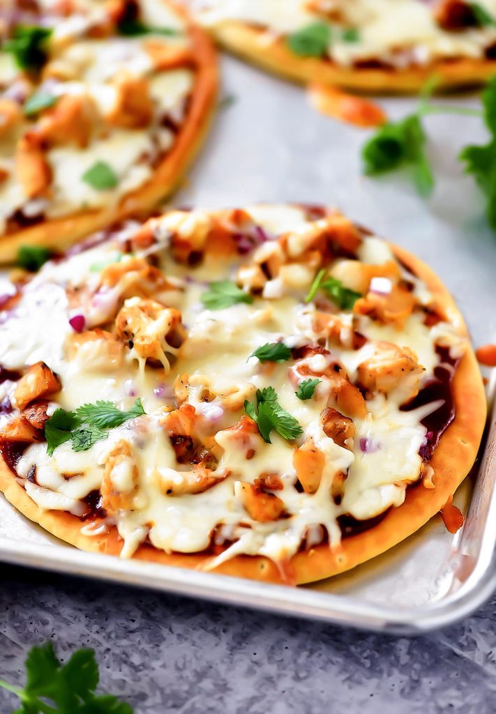 A BBQ chicken flatbread pizza topped with melted cheese, chicken, red onion, cilantro and barbecue sauce on a crispy flatbread crust.