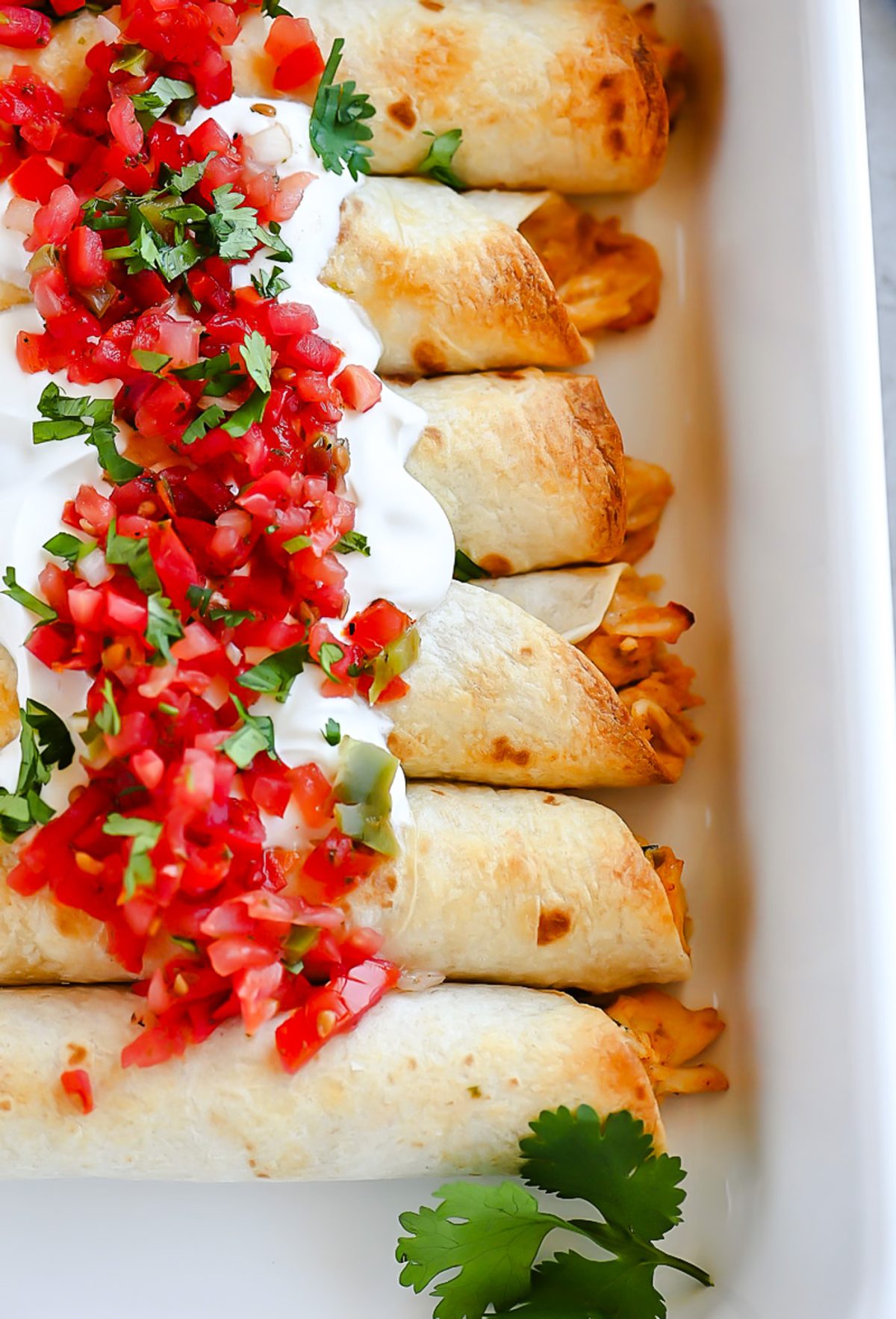Baked Chicken Taquitos are a crispy flour tortilla wrapped around a warm center of creamy and cheesy Mexican chicken.