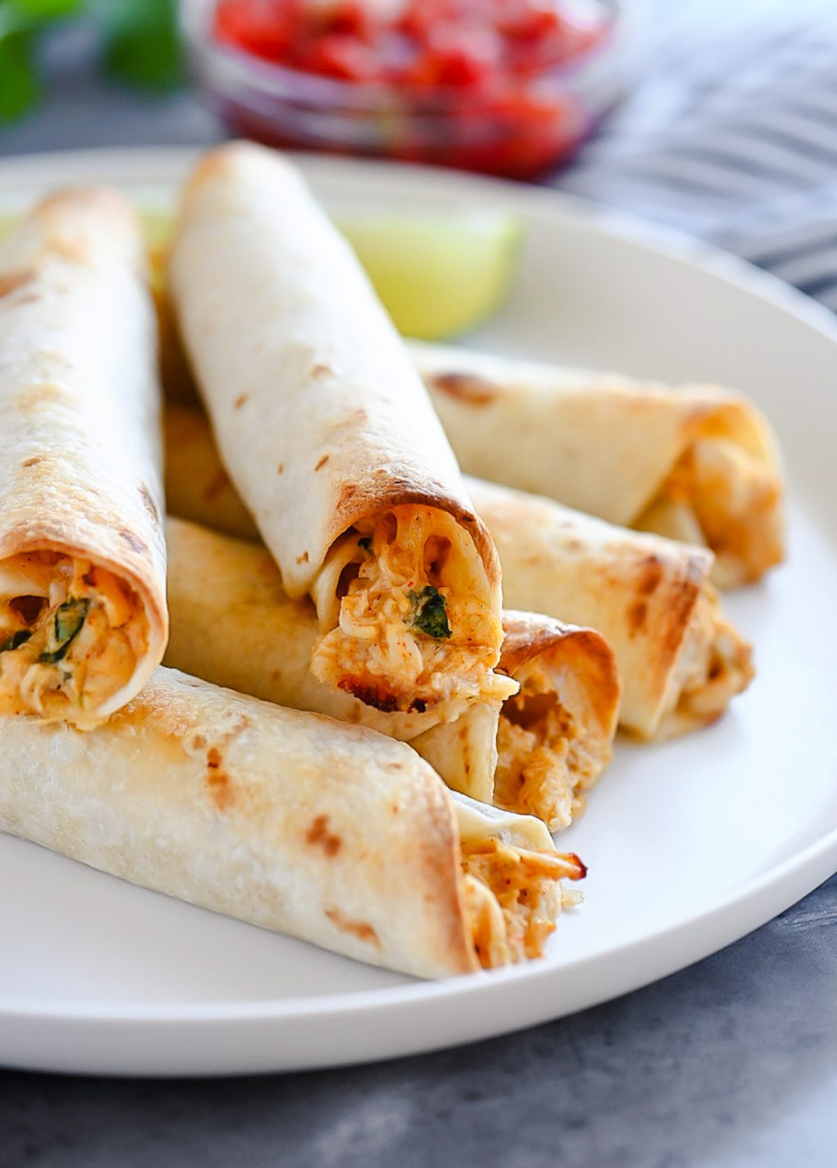 Baked Chicken Taquitos are a crispy flour tortilla wrapped around a warm center of creamy and cheesy Mexican chicken.