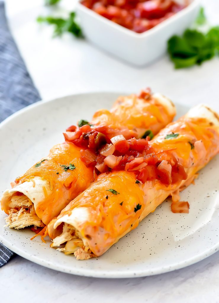 Shredded taco chicken covered in a salsa-ranch mixture, wrapped around flour tortillas, then covered in more salsa-ranch and cheese. Life-in-the-Lofthouse.com