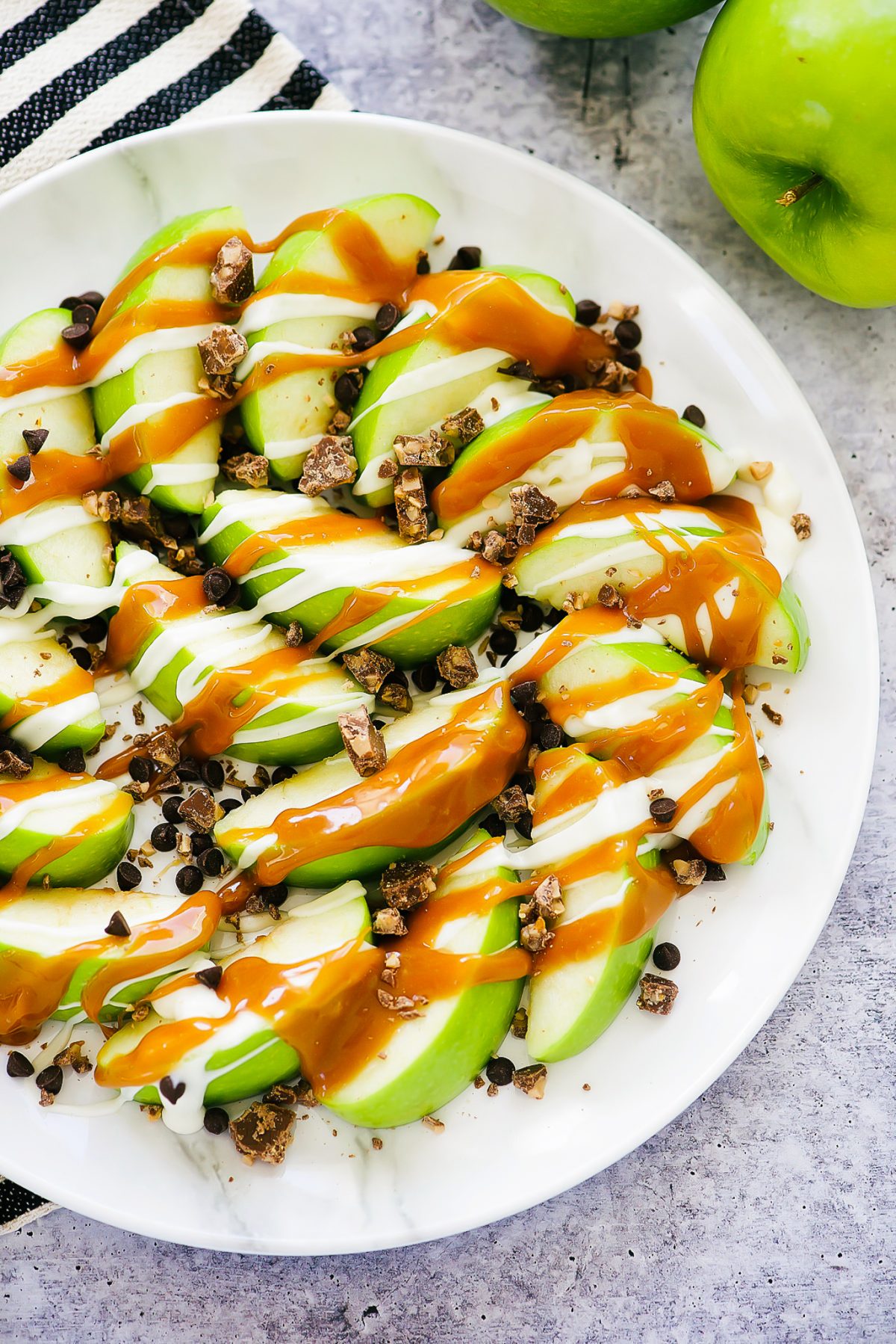 Caramel Apple Nachos start with slices of green apples then covered in warm caramel sauce, white chocolate and crushed candy bars. Life-in-the-Lofthouse.com