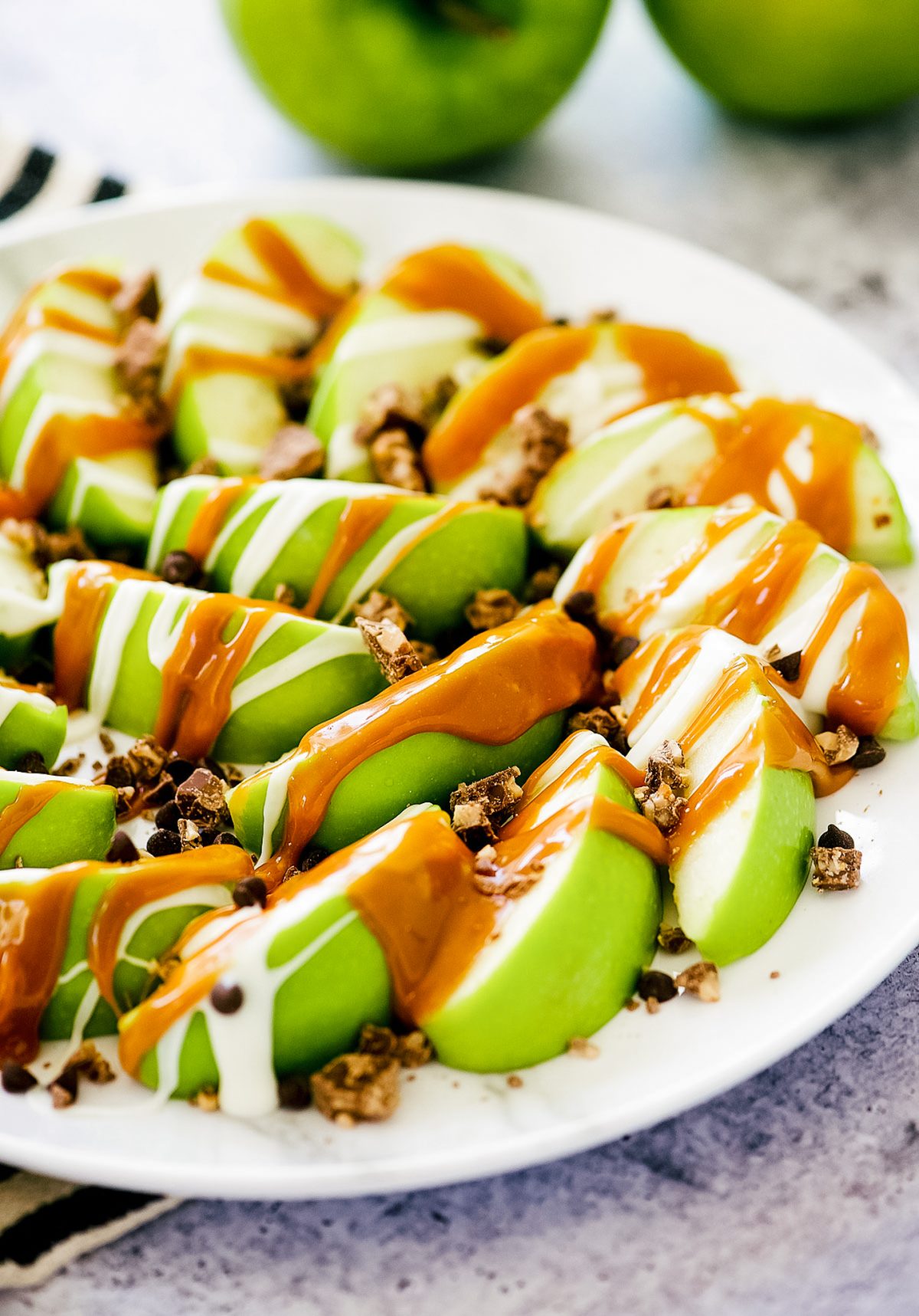 Caramel Apple Nachos start with slices of green apples then covered in warm caramel sauce, white chocolate and crushed candy bars. Life-in-the-Lofthouse.com