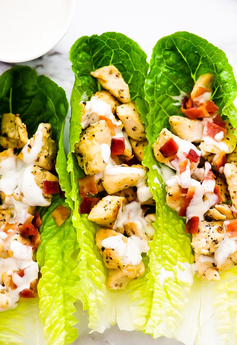 Seasoned chicken and crumbled bacon are filled inside of romaine lettuce leaves. They are topped off with ranch dressing.