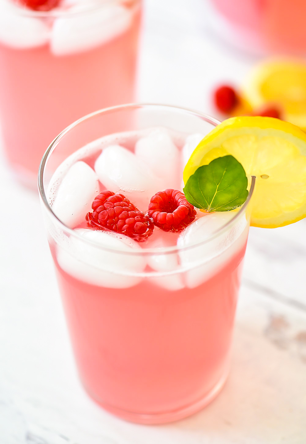 Lemonade with raspberry flavor. Garnished with raspberries, lemon and mint leaves.