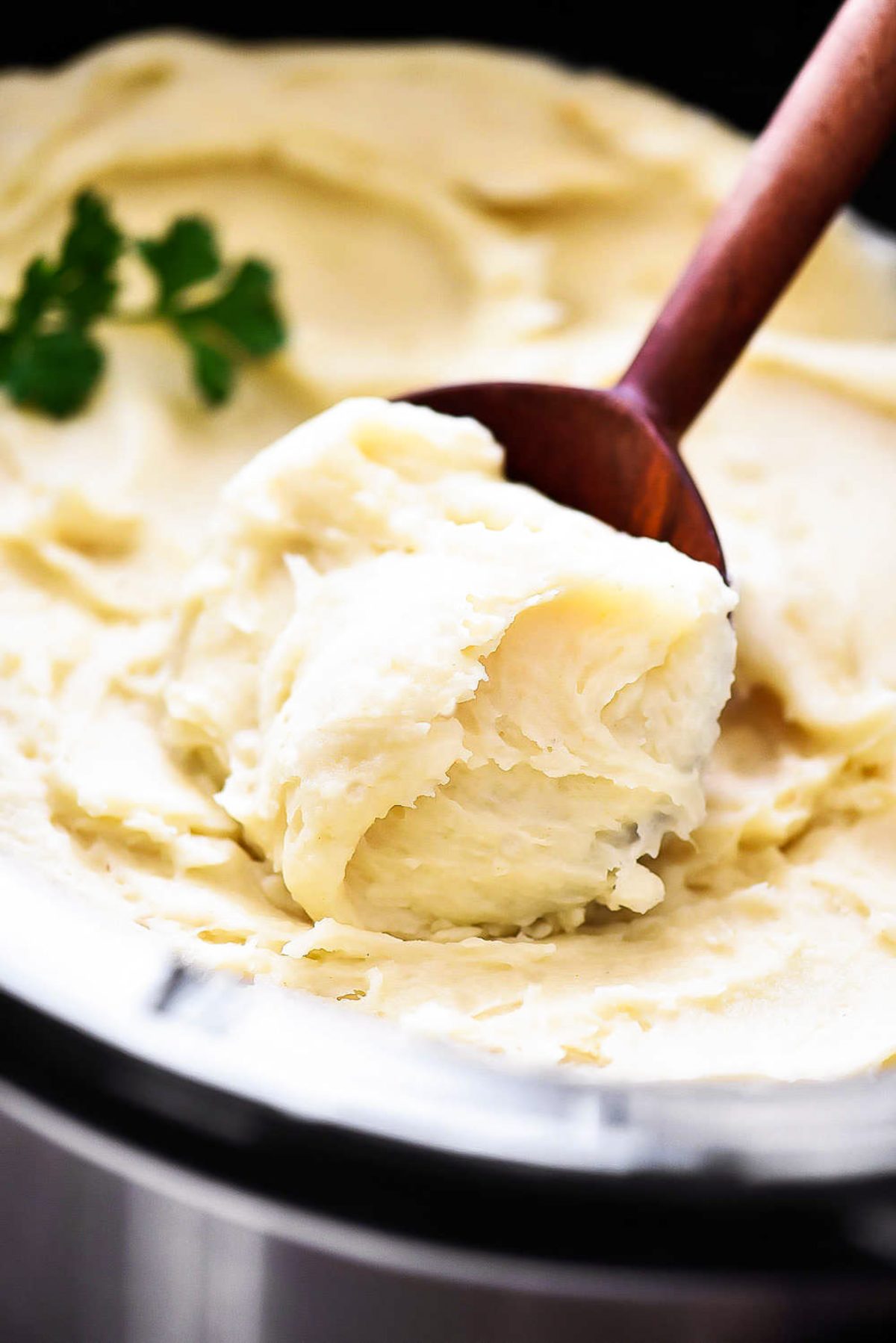 Crock Pot Creamy Mashed Potatoes with a wooden spoon