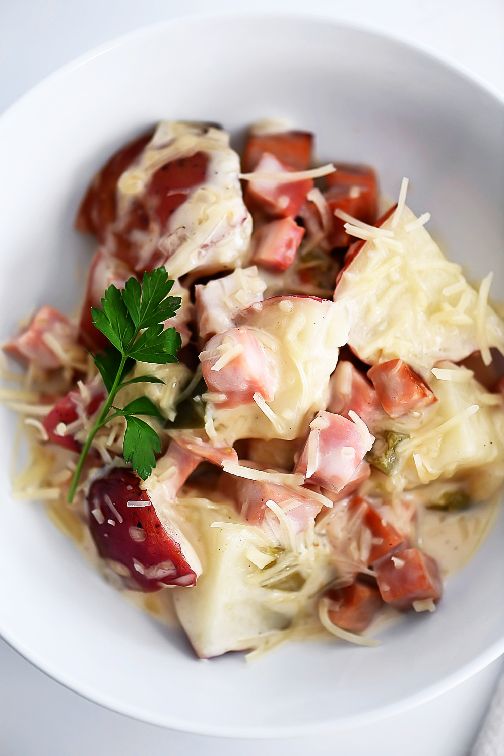 Potatoes, ham and Alfredo sauce slow cook in the crock pot.