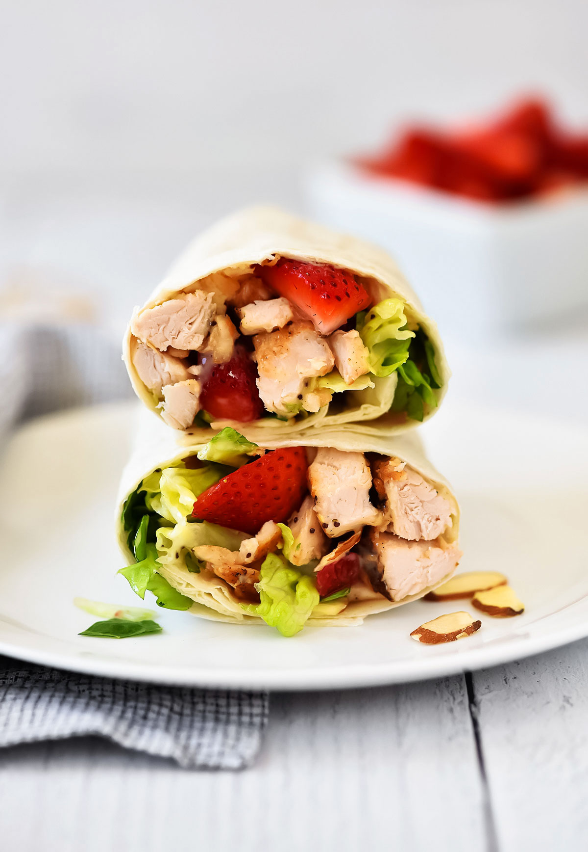 Strawberry Chicken Wraps cut in half sitting on top of each other on a white dish