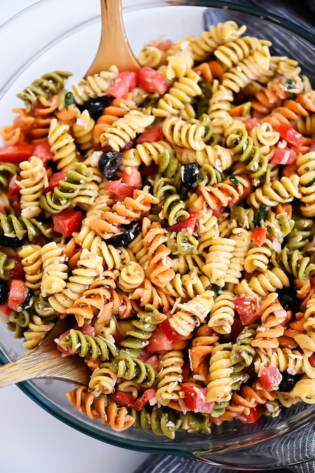 Tri Color Pasta Salad is filled with noodles, fresh veggies, and Parmesan cheese. It’s tossed in a creamy Caesar dressing and basil pesto