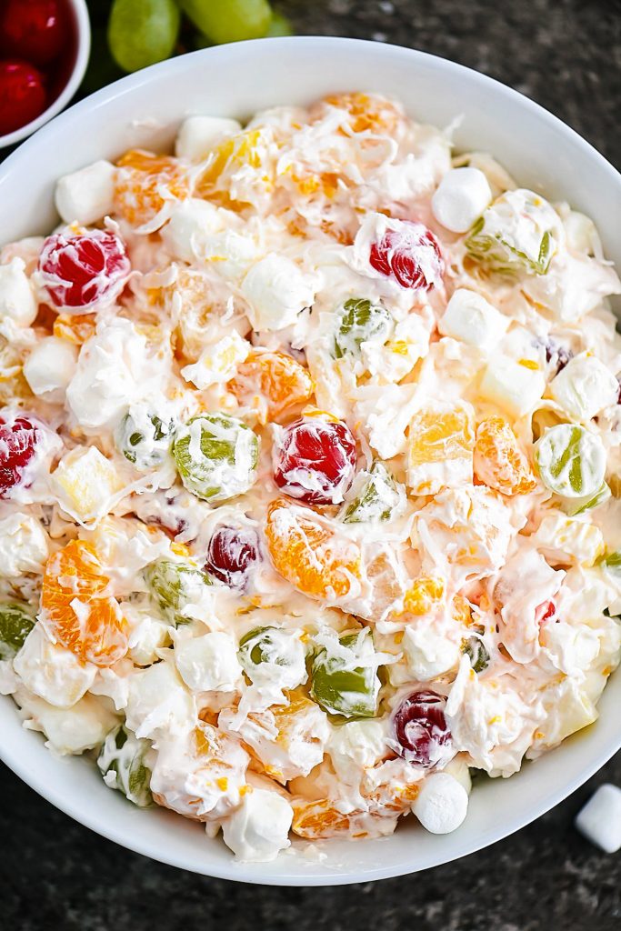 Ambrosia salad has apples, oranges, pineapples and grapes all tossed together in whipped topping and shredded coconut. Life-in-the-Lofthouse.com