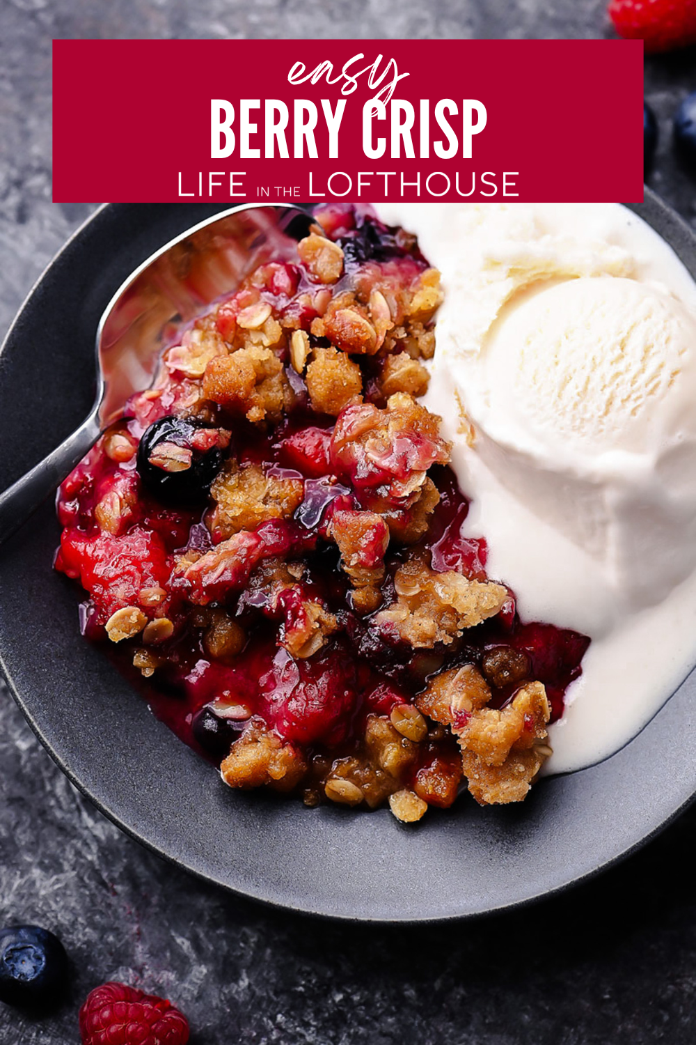A warm berry crisp with bubbling mixed berries and a golden oat crumble topping, served in a white dish with a scoop of melting vanilla ice cream on top.