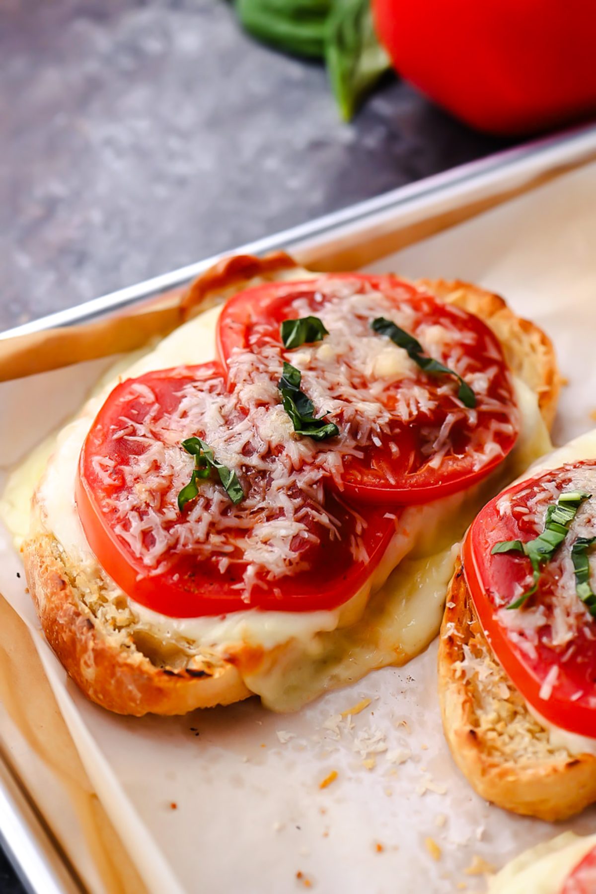 Sourdough pizza toast topped with melted mozzarella, fresh tomatoes, garlic, basil, and pizza sauce.