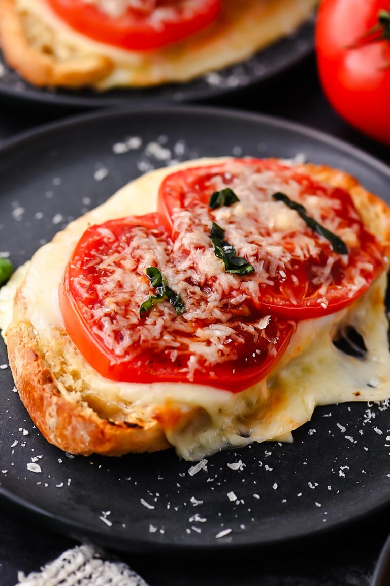 Sourdough pizza toast topped with melted mozzarella, fresh tomatoes, garlic, basil, and pizza sauce.