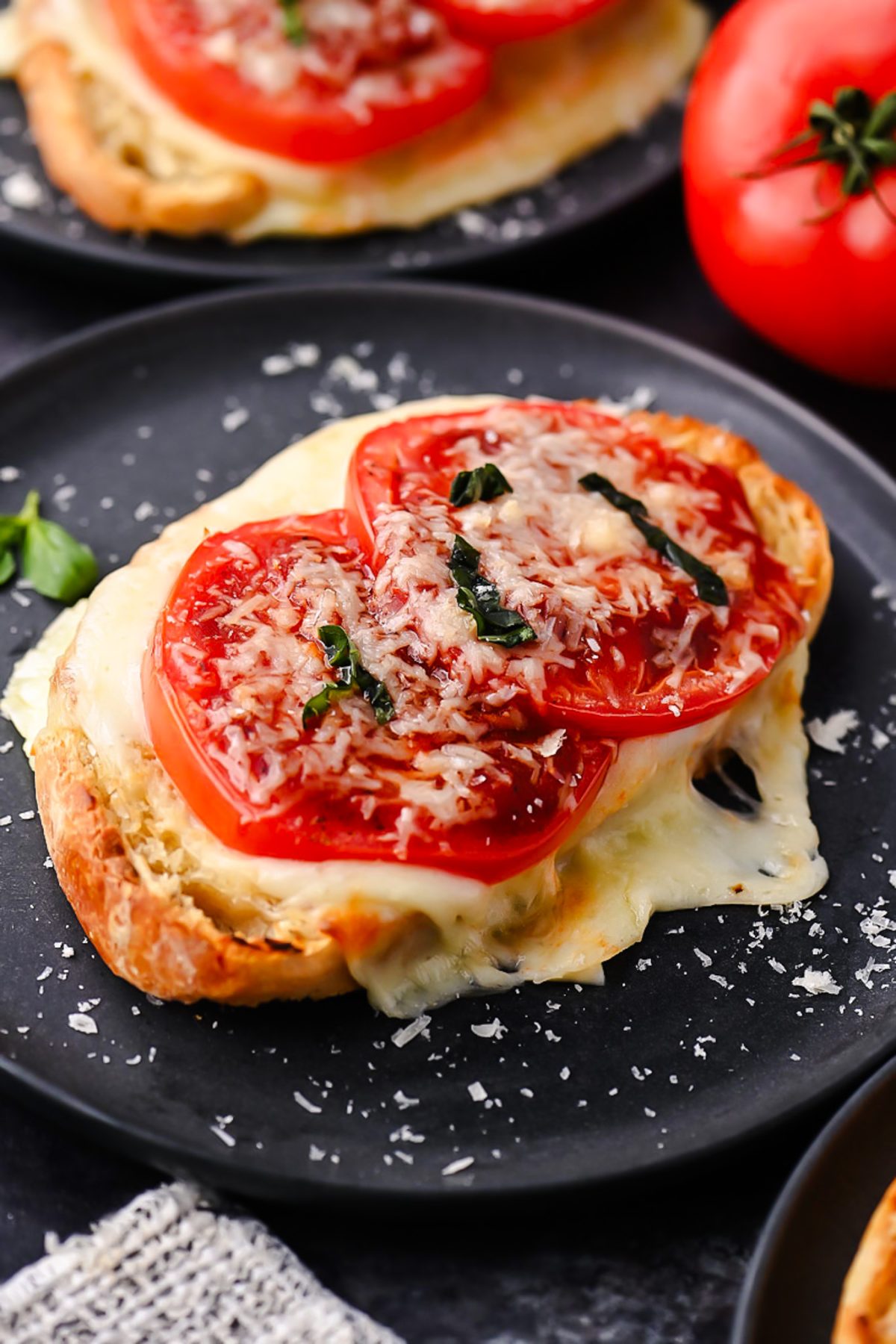 Sourdough pizza toast topped with melted mozzarella, fresh tomatoes, garlic, basil, and pizza sauce.