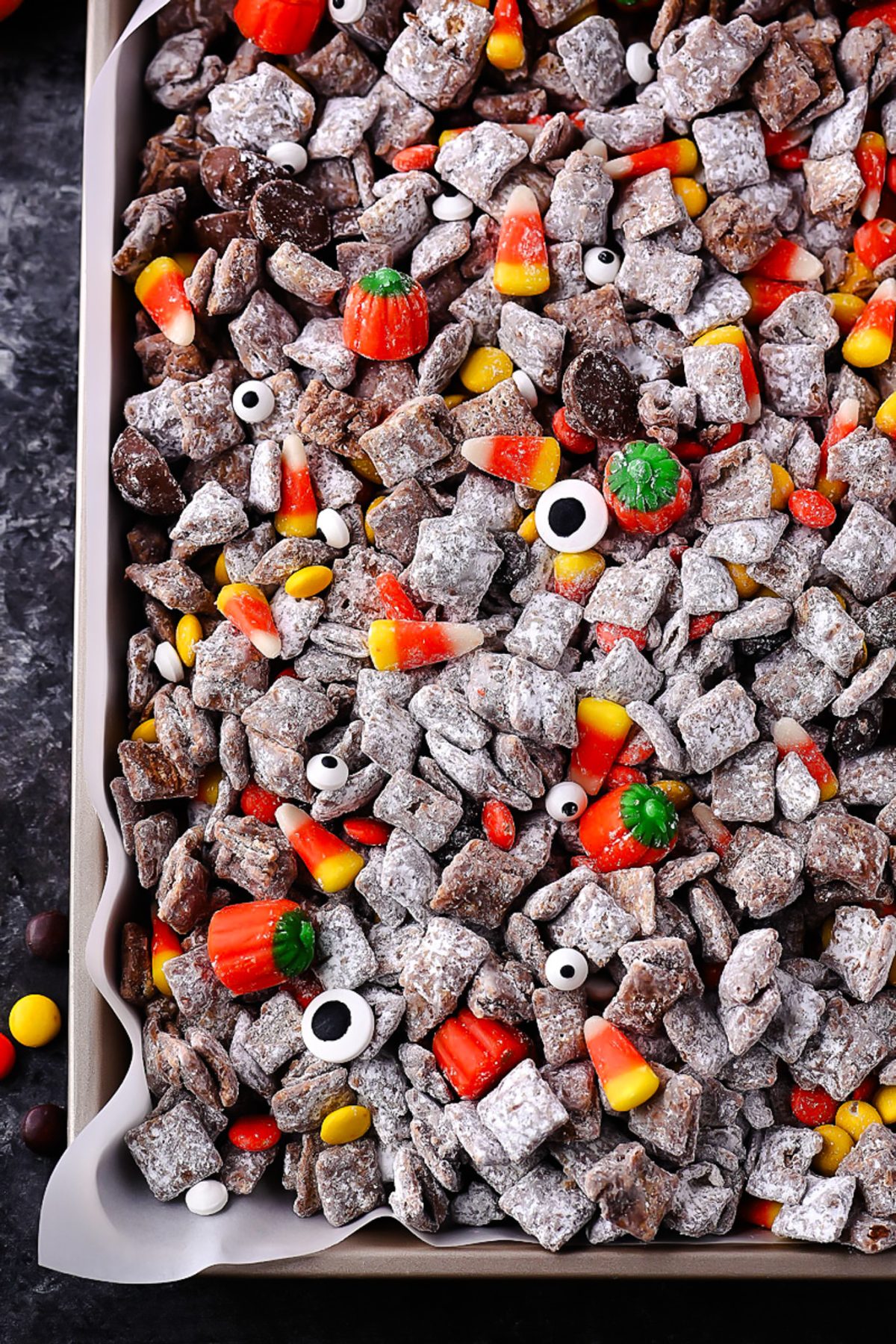 Halloween Muddy Buddies with rice Chex, chocolate, powdered sugar, and Halloween candy.