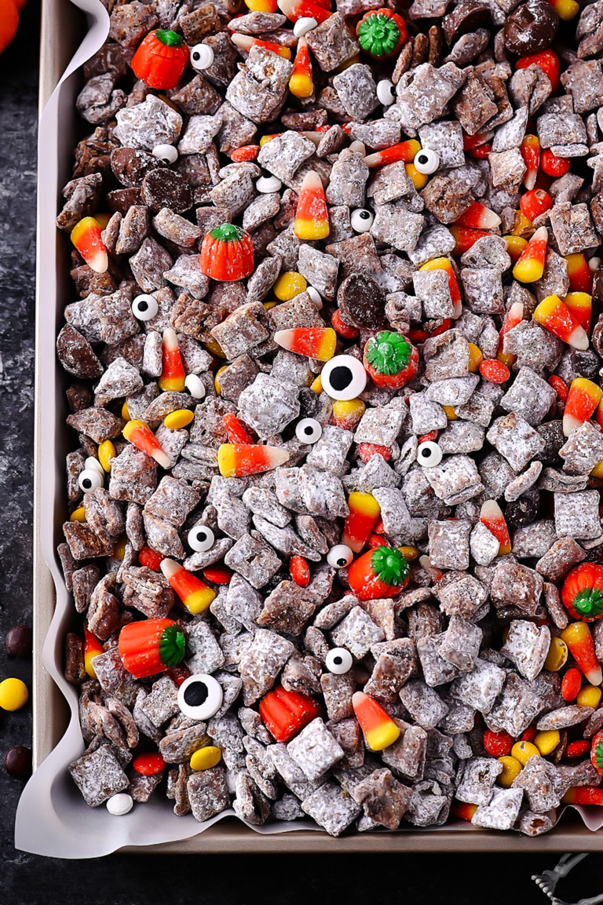 Halloween Muddy Buddies with rice Chex, chocolate, powdered sugar, and Halloween candy.