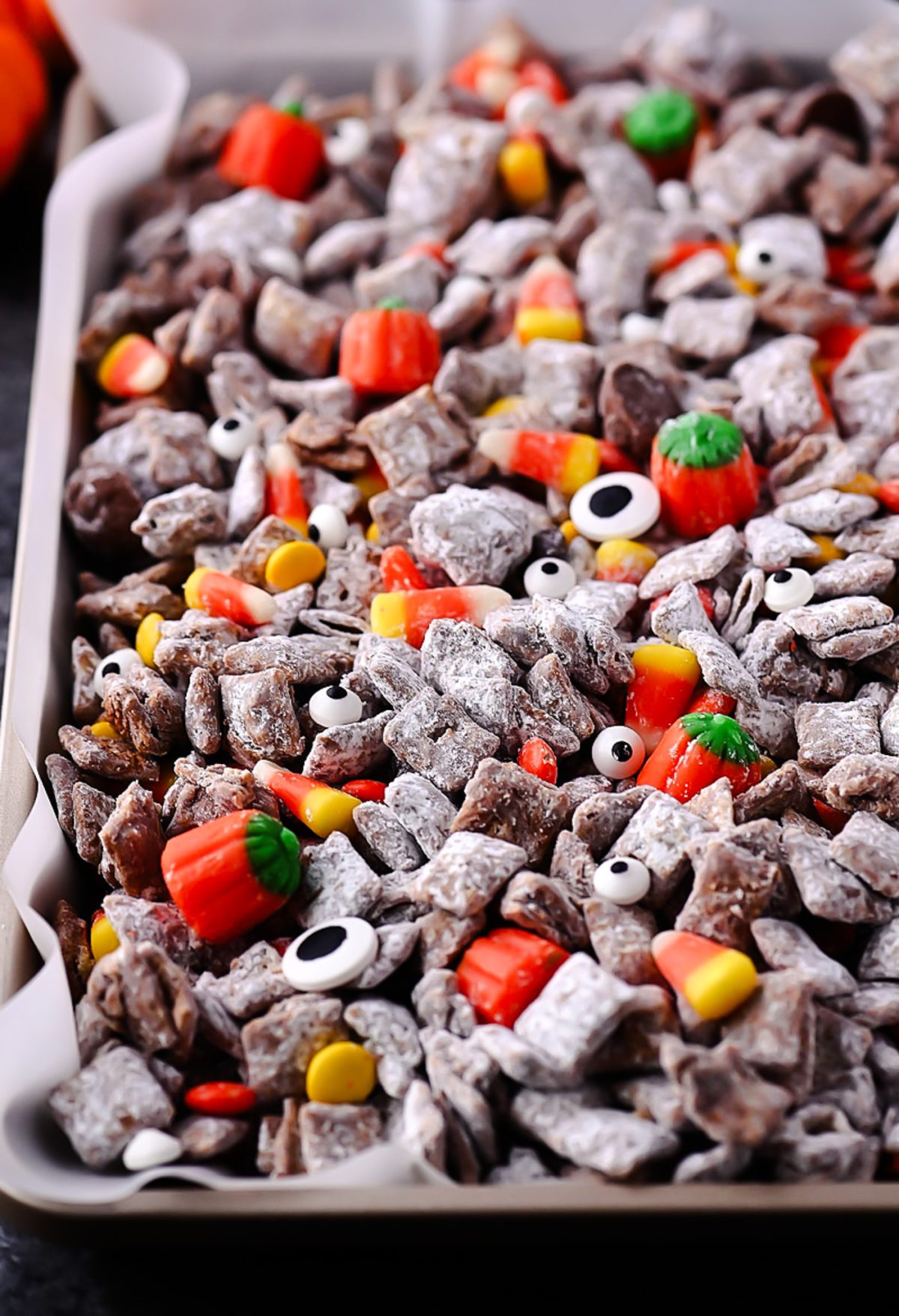 Halloween Muddy Buddies with rice Chex, chocolate, powdered sugar, and Halloween candy.